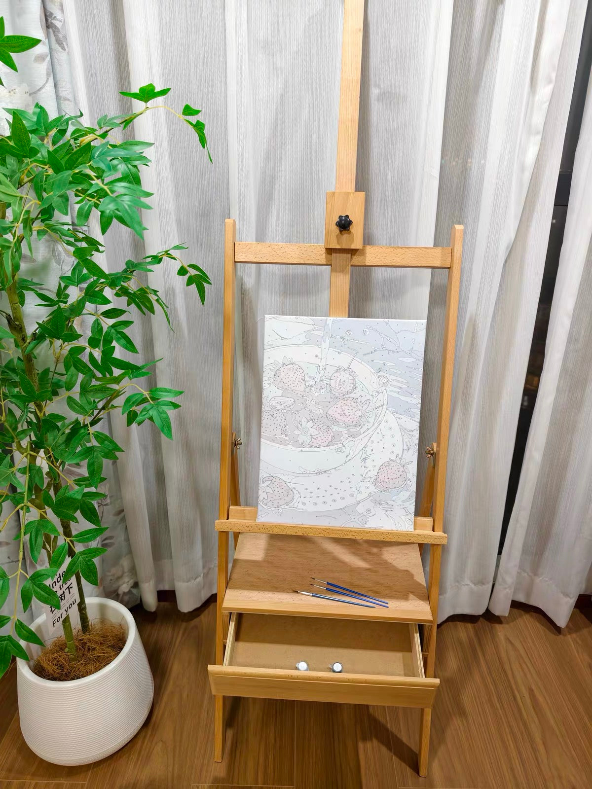 Blank canvas on a wooden easel beside a houseplant