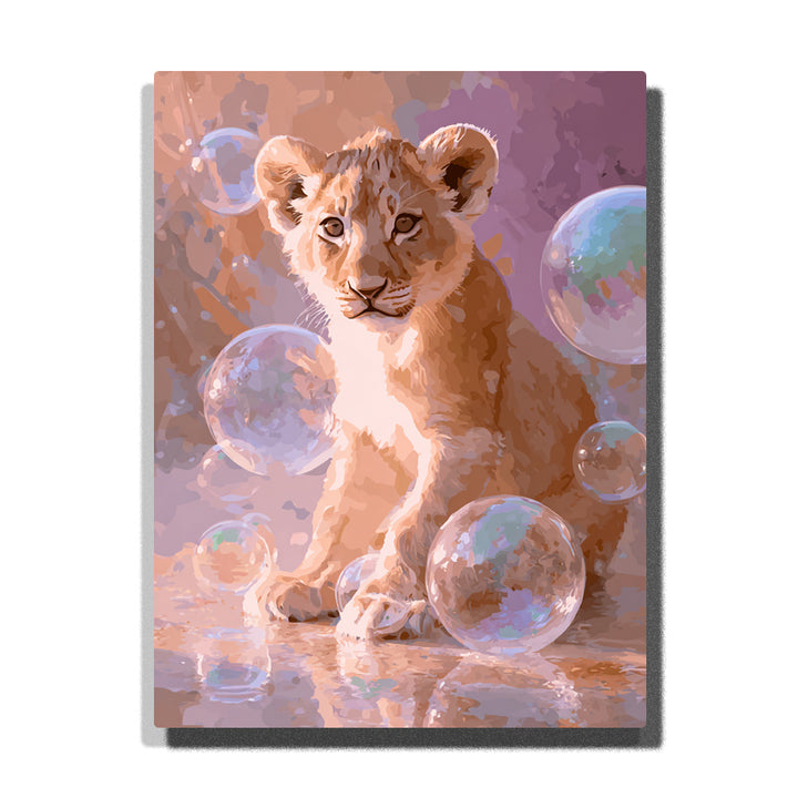 Lion cub sitting among iridescent bubbles with golden fur, cream chest, rounded ears, peach-lavender background, and soft reflective light, paint by numbers wall art by PaintEasy