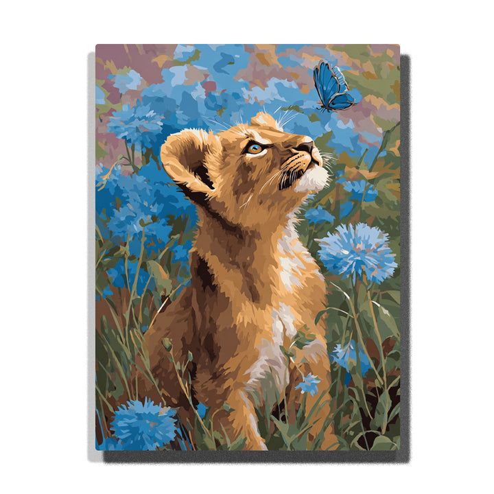 Lion cub looking up at a blue butterfly among cornflowers with golden-brown fur, cream chest, blue blossoms, tall grass, and soft meadow light, paint by numbers wall art by PaintEasy