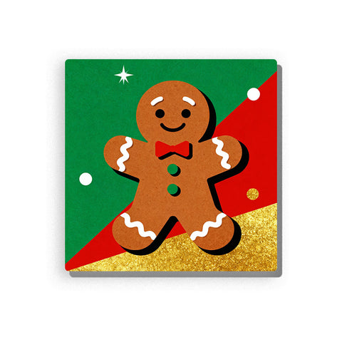 Smiling gingerbread cookie with red bow tie, green buttons, white icing trim, black smiling face, red and green Christmas background, gold glitter-style section, white snow dots, and small star, Paint by Numbers kit for kids by PaintEasy.