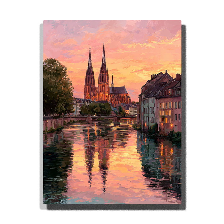 Twin cathedral spires above a glowing canal at sunset with historic waterfront buildings, pink gold reflections, and warm European city light, city paint by numbers wall art by PaintEasy