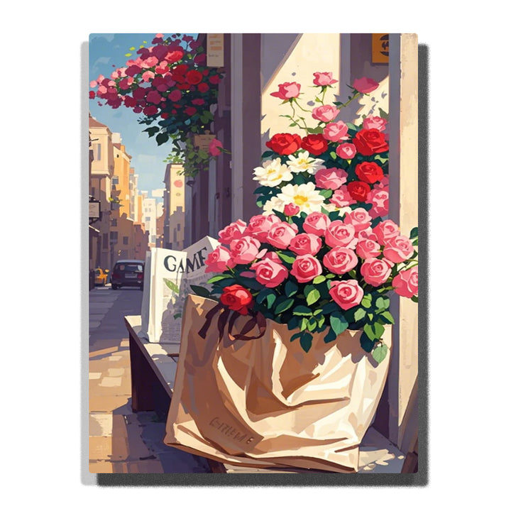 Pink and red roses in a paper bag by a sunlit flower shop window, with a narrow city street and hanging basket in the background in this Paint by Numbers artwork.