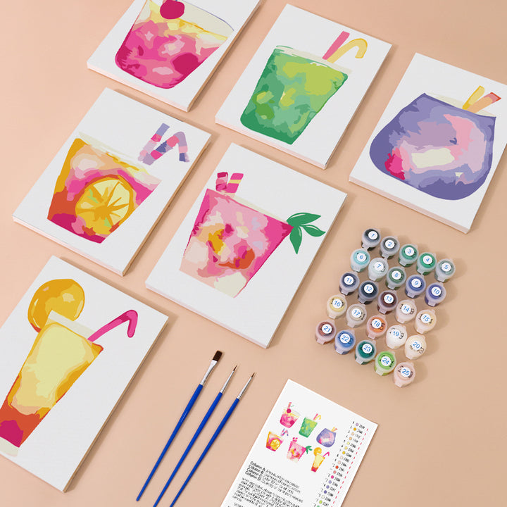 Six mini paint by numbers canvases arranged in a set, each showing a different colorful drink illustration including a pink fruit cocktail, green iced drink, purple smoothie, orange citrus drink with lemon slice, strawberry pink beverage with mint leaf, and a tropical mixed fruit drink, all in a simple and playful style with bold colors and soft gradients.