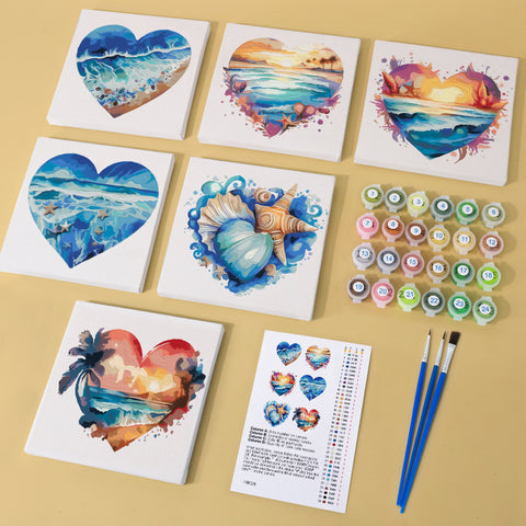 Six mini paint by numbers canvases arranged in a set, each featuring a heart-shaped ocean landscape illustration including beach waves, sunset seas, tropical coastlines, seashell compositions, and island silhouettes. Each artwork uses a bold flat illustration style with layered colors, soft gradients, and expressive ocean textures framed inside heart shapes.