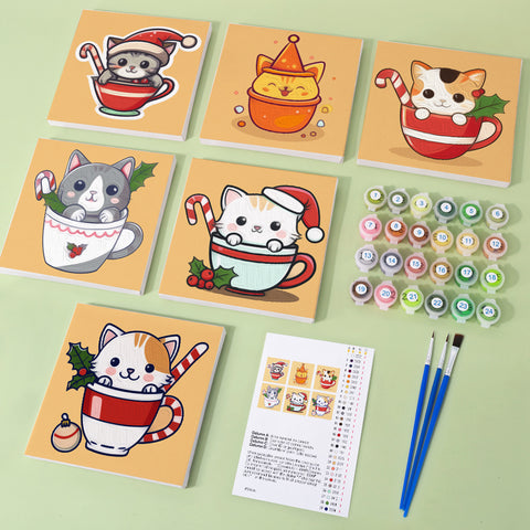 Six mini paint by numbers canvases arranged in a set, each featuring a festive Christmas cat cup illustration with cute cats wearing Santa hats inside holiday mugs decorated with candy canes, holly leaves, and seasonal ornaments. Each artwork uses a flat illustration style with warm colors, simplified shapes, and playful Christmas-themed design.