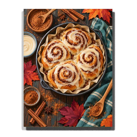 Iced cinnamon rolls in a baking pan surrounded by autumn leaves and spices